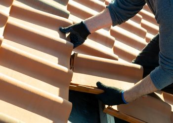 Closeup of worker hands installing yellow ceramic roofing tiles Closeup of worker hands installing yellow ceramic roofing tiles